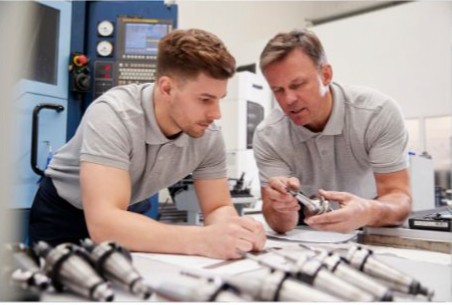 An apprentice and their tutor working together at the machine