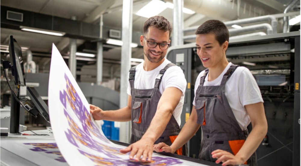Two print workers checking a printed sheet together
