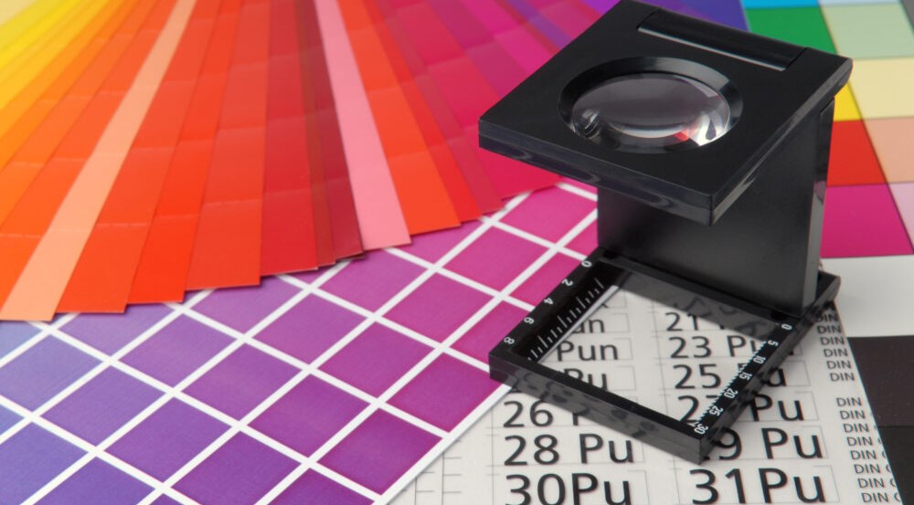 Colour swatches and a printer's loupe on a press sheet
