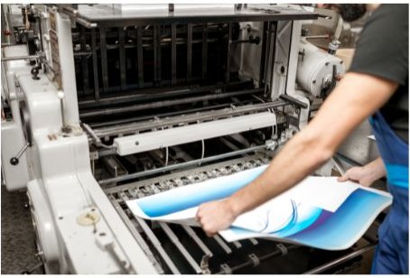 A press operator checking a printed sheet